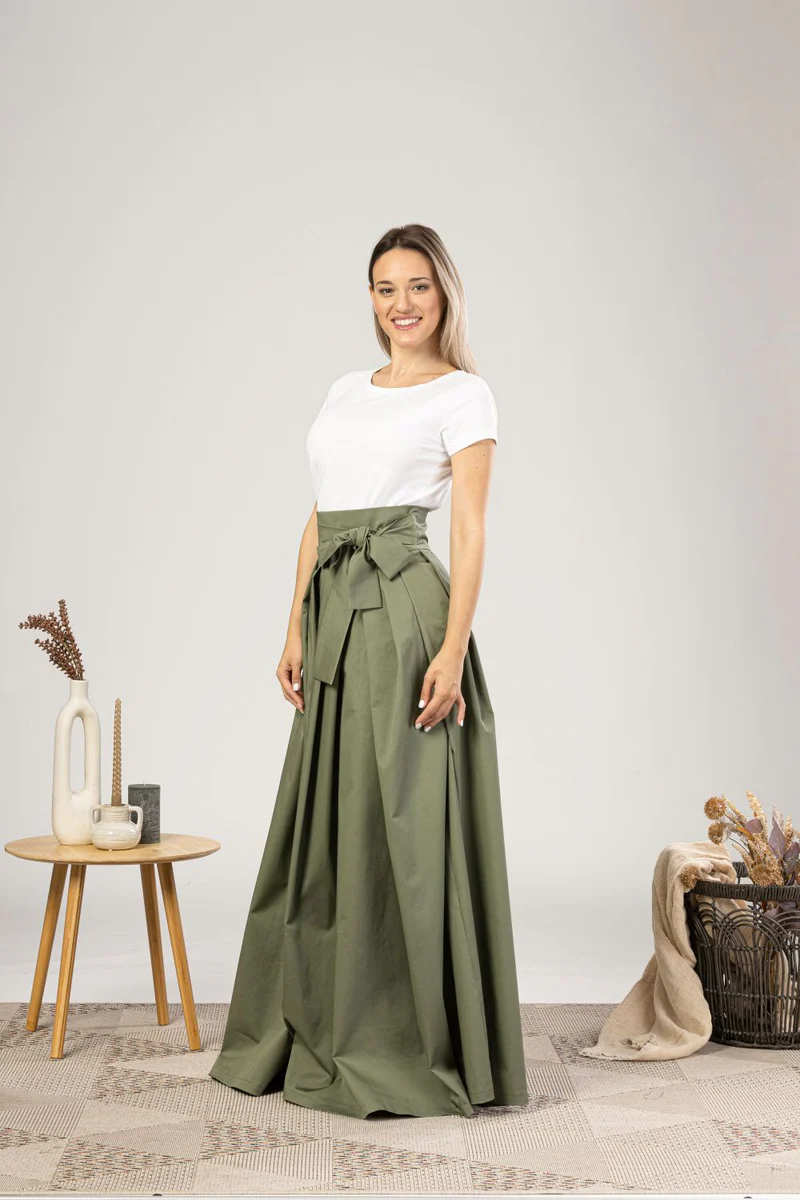 Side profile of dark green skirt with pleats.

